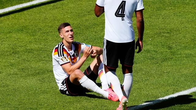 Deutschlands Nico Schlotterbeck (l.) sitzt verletzt am Boden